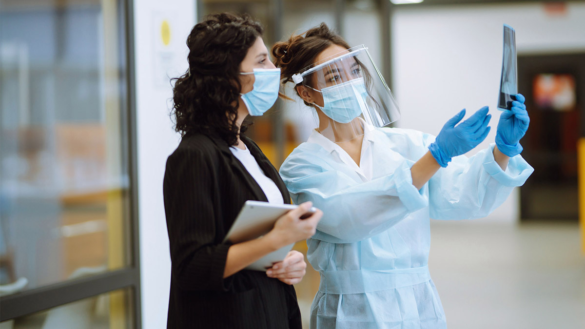 Two people in surgical masks holding up an x-ray image